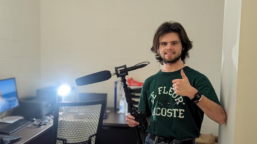 Henry Rountree on set with a boom mic, giving a thumbs up