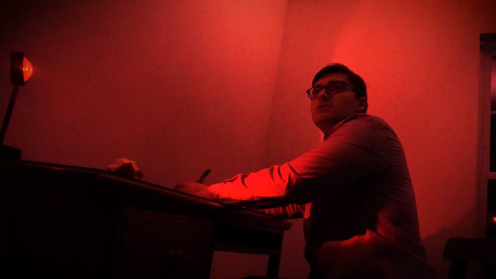 A writer at a desk under red light