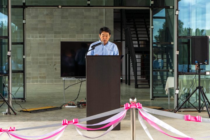 A speech at the podium behind the ceremonial ribbons